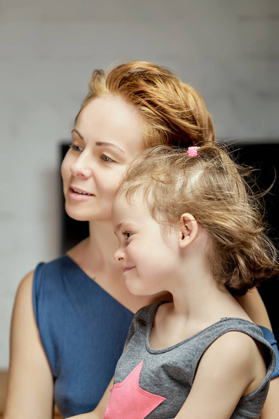 Όμορφη μικρή κόρη με τη μαμά ποζάρει στο στούντιο σε γκρι φόντο - Φωτογραφία, εικόνα