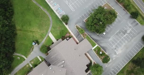 Een luchtfoto van een typisch Amerikaans suburbane gebied met een mix van residentiële, commerciële en natuurlijke ruimtes verbonden door opritten naar straten en landweggetjes met ruimten voor parkeergarages, gazons, bomen, struiken en andere plantage. - Video