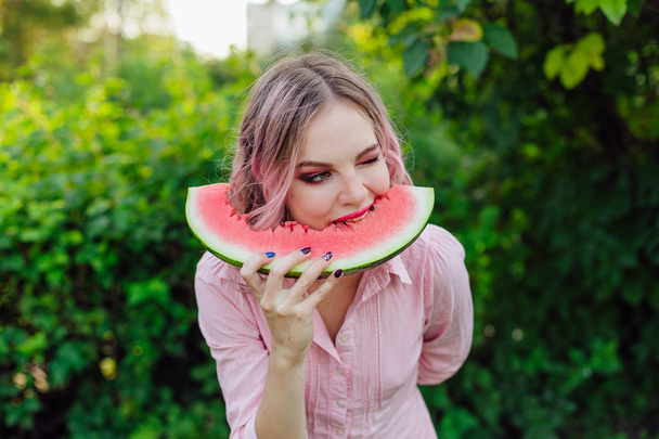 Beautiful young woman with pink hair enjoying watermelon - Foto, afbeelding
