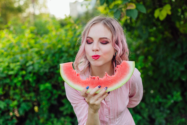 Beautiful young woman with pink hair enjoying watermelon - Foto, Bild
