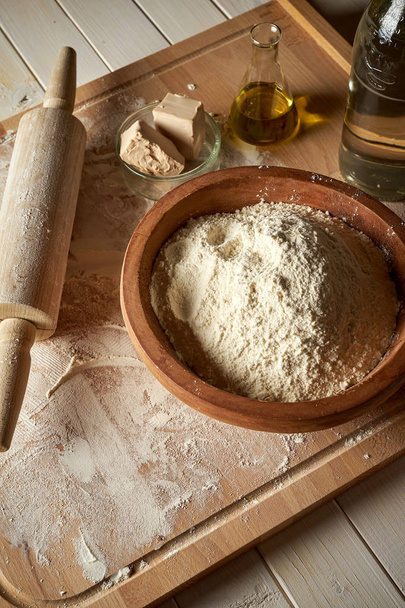 Ingredience na cukrářské desce s moukou a válcovými špendlíkem na stole - Fotografie, Obrázek