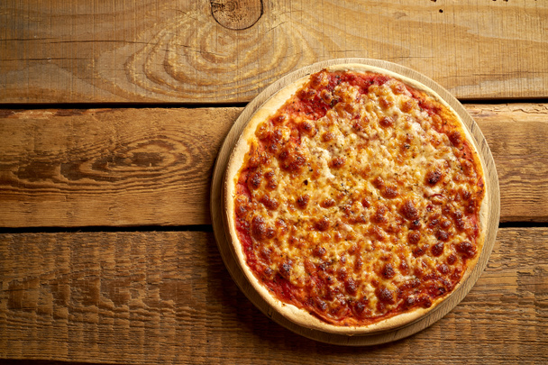 Top uitzicht van zelfgemaakte Italiaanse pizza Margherita op oude houten tafel - Foto, afbeelding