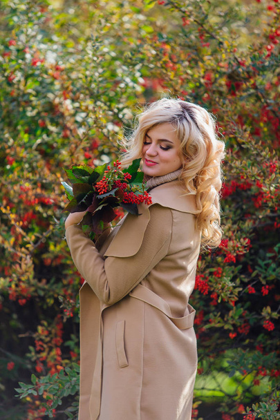 Beautiful elegant woman standing next barberry bush in autumn park - Foto, Imagem