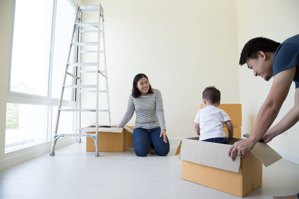Happy Asian family with cardboard boxes in new house at moving day - Fotoğraf, Görsel