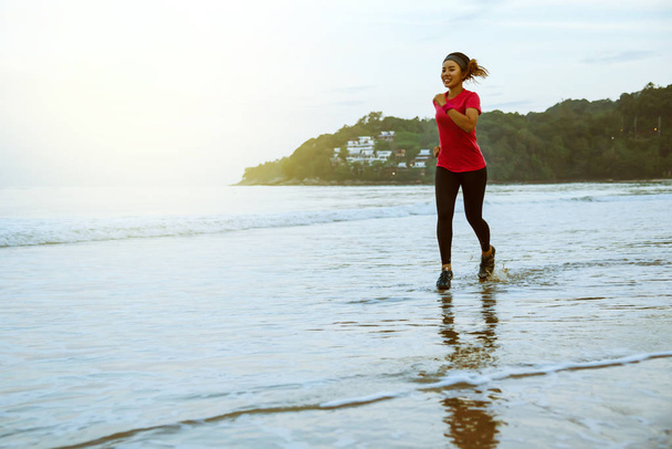 Vrouw joggen workout op het strand in de ochtend. Ontspan met de zee lopen. Springen en plezier op de training. zee, strand, natuur, buitenshuis, vakantie, sport, oefening, ontspannen, reizen Thailand. - Foto, afbeelding