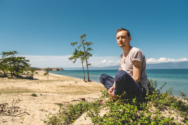 Ember utazó pihenés a strandon Olkhon sziget kilátással a víz a tó és a hegyek és a kék ég - Fotó, kép