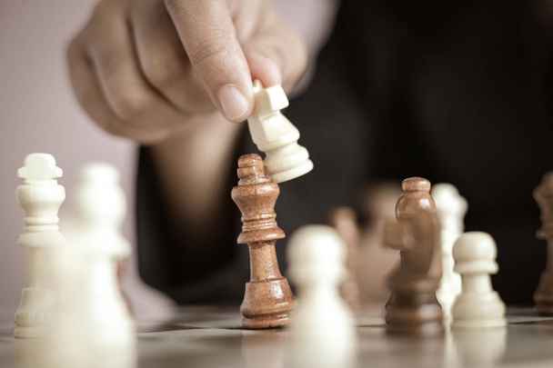 Закройте руку бизнес-леди, играющей на шахматной доске
  - Фото, изображение