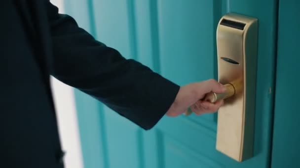 Man in dark blue suit opens a massive turquoise door and enters a room. Close up of a door handle. - Filmati, video