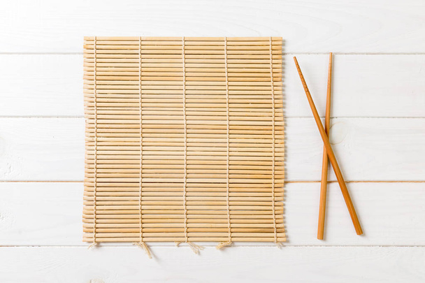 две палочки суши с пустым бамбуковым ковриком или деревянной доской на деревянном фоне
 - Фото, изображение