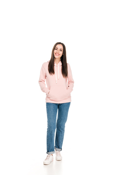 full length view of smiling girl in casual outfit standing with hands in pockets isolated on white - Fotoğraf, Görsel