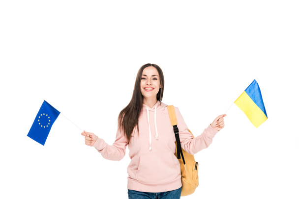 estudiante sonriente con mochila sosteniendo banderas ucranianas y europeas aisladas en blanco
 - Foto, Imagen