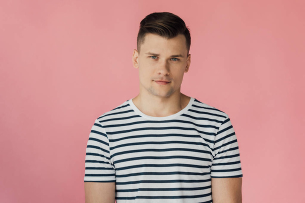 front view of handsome man in striped t-shirt looking at camera isolated on pink - Фото, изображение