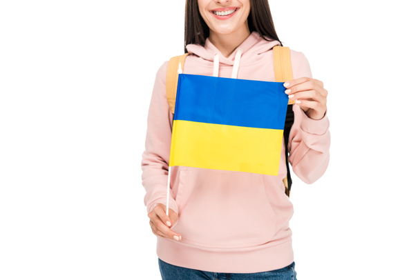 白に隔離されたウクライナの旗を持つバックパックを持つ笑顔の学生のトリミングされたビュー - 写真・画像