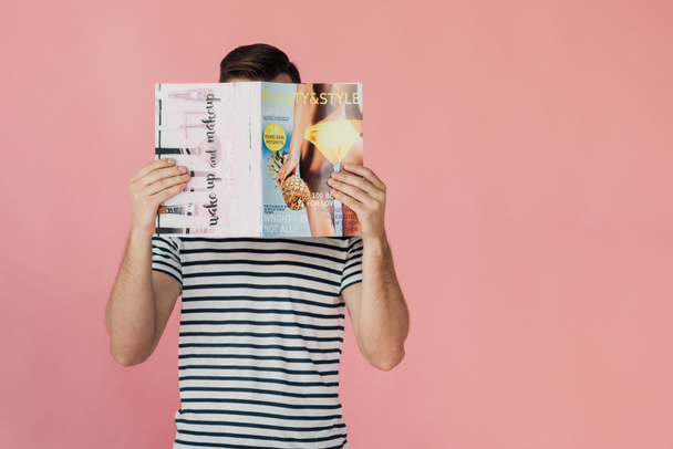 Frontansicht eines Mannes im gestreiften T-Shirt, der Magazin auf rosa isoliert liest - Foto, Bild