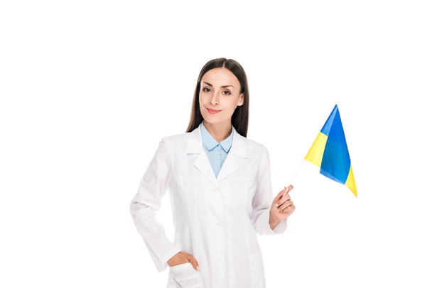 白で孤立したウクライナの旗を持つ白いコートで笑顔の医者 - 写真・画像