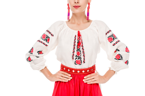 bijgesneden weergave van jonge vrouw in nationaal Oekraïens kostuum staande met handen op heupen geïsoleerd op wit - Foto, afbeelding