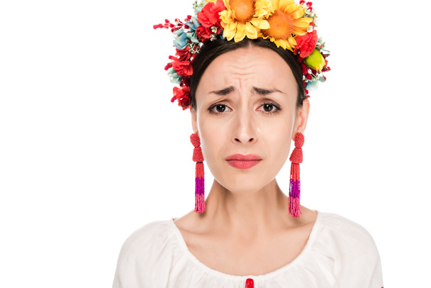 zdenerwowany brunetka młoda kobieta w ukraińskiej haftowanej koszulce i wieniec kwiatowy na białym tle - Zdjęcie, obraz
