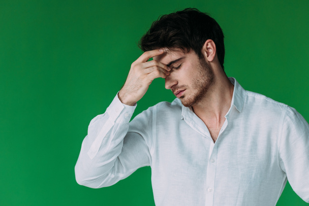 tired man in white shirt touching face with closed eyes isolated on green - Fotoğraf, Görsel