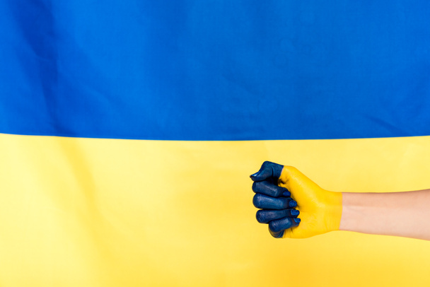 partial view of painted hand on Ukrainian flag background - Fotografie, Obrázek
