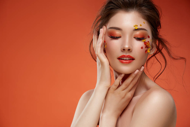 портрет привлекательной женщины с цветами на лице на оранжевом фоне
 - Фото, изображение