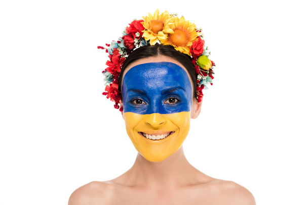 mujer joven desnuda en corona floral con bandera ucraniana pintada en piel sonriente aislada en blanco
 - Foto, Imagen