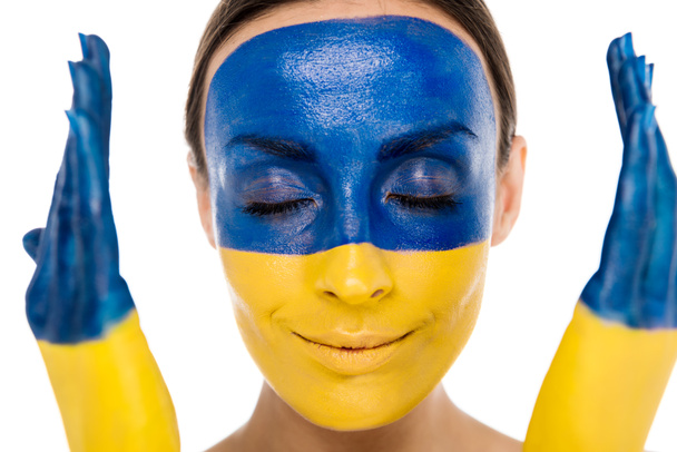 Młoda kobieta z pomalowaną Ukrainką flagą na skórze i zamkniętymi oczami na białym - Zdjęcie, obraz