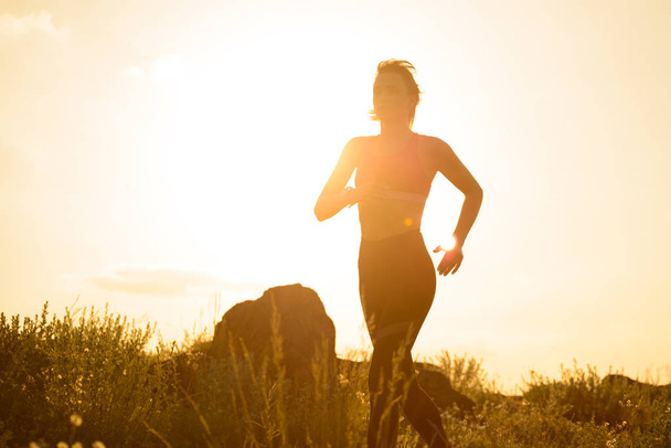 Fiatal gyönyörű nő fut a Mountain Trail a Hot Summer Sunset. Sport és aktív életmód. - Fotó, kép