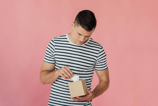 man in striped t-shirt holding napkins isolated on pink - Foto, Imagen