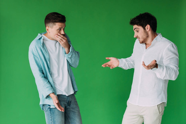 two worried men in shirts gesturing isolated on green - Φωτογραφία, εικόνα