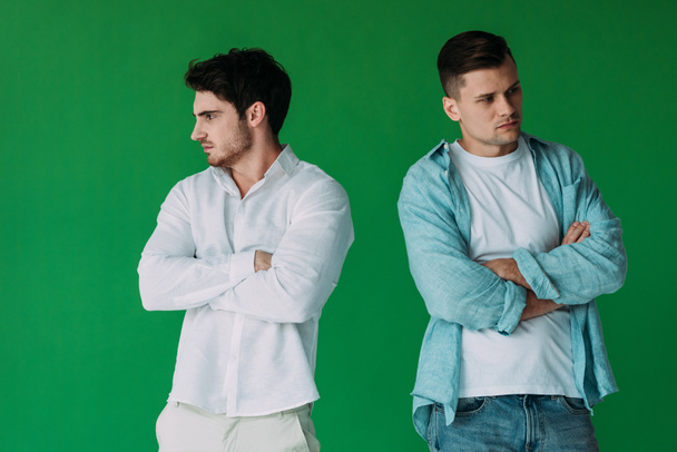 two offended men in shirts standing with crossed arms isolated on green - Photo, Image