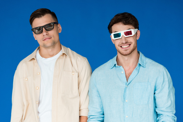 vista frontal de dos amigos sonrientes en gafas 3D aisladas en azul
 - Foto, imagen