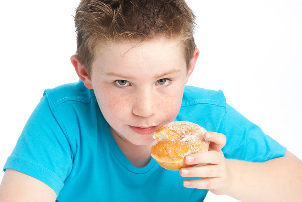 youny αγόρι που τρώει ένα ζαχαρούχο ντόνατ. - Φωτογραφία, εικόνα
