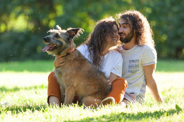 Happy beautiful curly young couple sits on the grass with with   - Foto, Bild