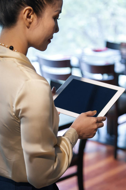 Female restaurant manager reading information on tablet computer  - Photo, Image