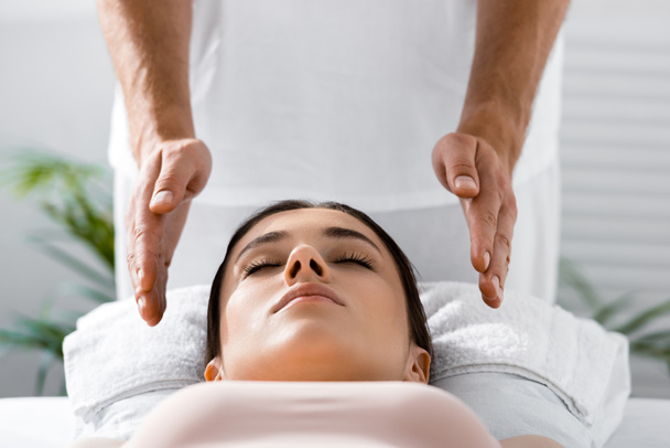 cropped view of healer standing near patient on massage table and cleaning aura - Foto, Imagem