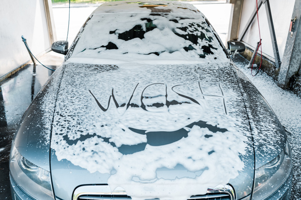 wassen belettering op moderne auto met wit schuim  - Foto, afbeelding