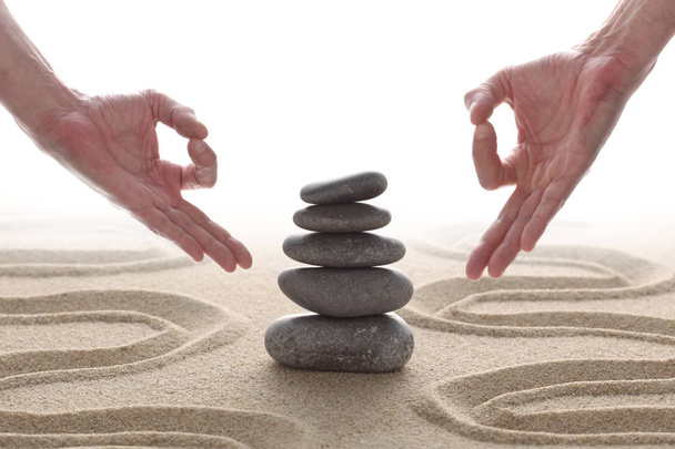 Zen stenen opgestapeld op raked zand met twee handen in om positie en kopieer ruimte voor uw tekst - Foto, afbeelding