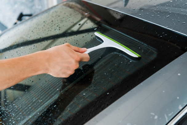 περικομμένη όψη του ανθρώπου κρατώντας το σφουγγάρι και πλύσιμο υγρό παράθυρο του αυτοκινήτου  - Φωτογραφία, εικόνα
