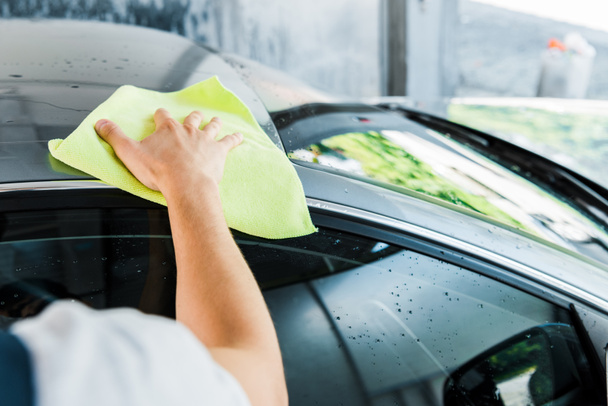 selektywnej ostrości myjki samochodowej trzymające zieloną szmatką i sprzątanie samochodu  - Zdjęcie, obraz