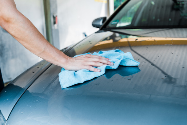 cropped view of man cleaning wet car with blue rag  - Valokuva, kuva