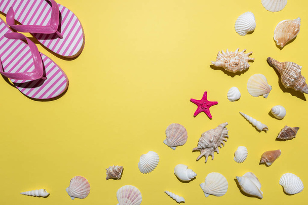 Creative composition with seashells and beach slippers on bright yellow background. Summer minimal concept. - 写真・画像