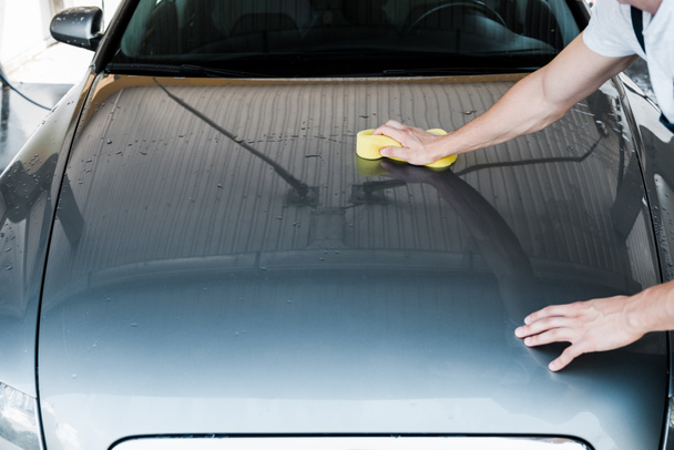 περικομμένη όψη του ανθρώπου κρατώντας κίτρινο σφουγγάρι, ενώ ο καθαρισμός Auto - Φωτογραφία, εικόνα