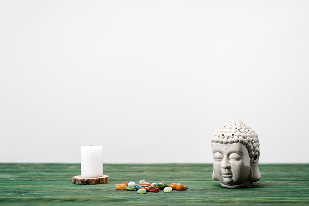 buddha statuette, candle and colorful semiprecious stones on wooden surface isolated on white - Photo, Image