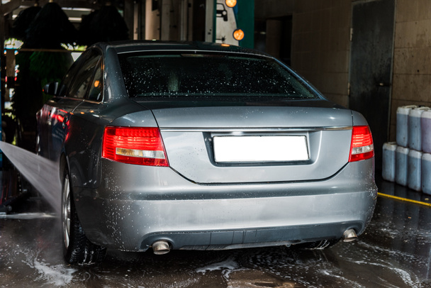 πίεση νερού σε γκρίζο αυτοκίνητο στην υπηρεσία πλύσης αυτοκινήτου  - Φωτογραφία, εικόνα