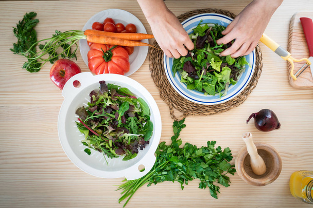 manos de la mujer preparando verduras mientras cocina ensalada saludable en la cocina
 - Foto, Imagen
