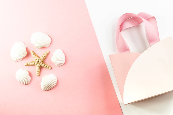 Flat lay top view Pink gift bag, Starfish and seashells on a pink background.  - Fotó, kép