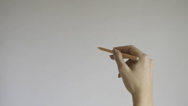  Το χέρι της γυναίκας κρατώντας ένα ξύλινο μολύβι σε απομονωμένο φόντο - Φωτογραφία, εικόνα