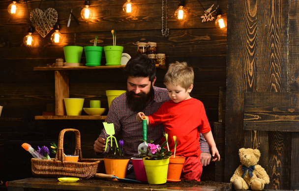 bearded man and little boy child love nature. Father and son. Fathers day. happy gardeners with spring flowers. Flower care. Soil fertilizers. Family day. Greenhouse. Achieve only best results - Foto, Bild