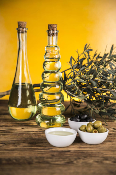 Aceite de oliva, olivo y aceitunas verdes y negras en una lengüeta de madera
 - Foto, imagen