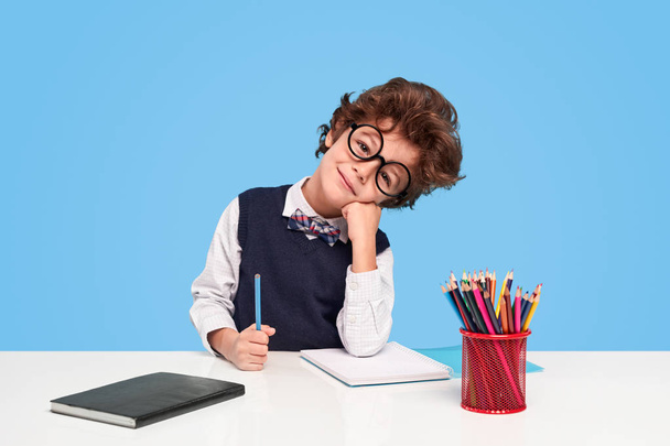 Cute schoolboy sitting at desk - Фото, изображение